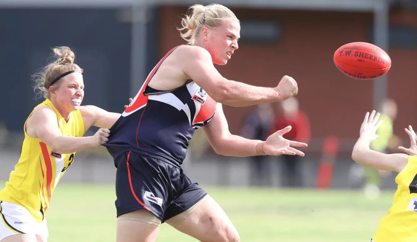 Player passing the ball while being tackled in match Player passing the ball while being tackled in match