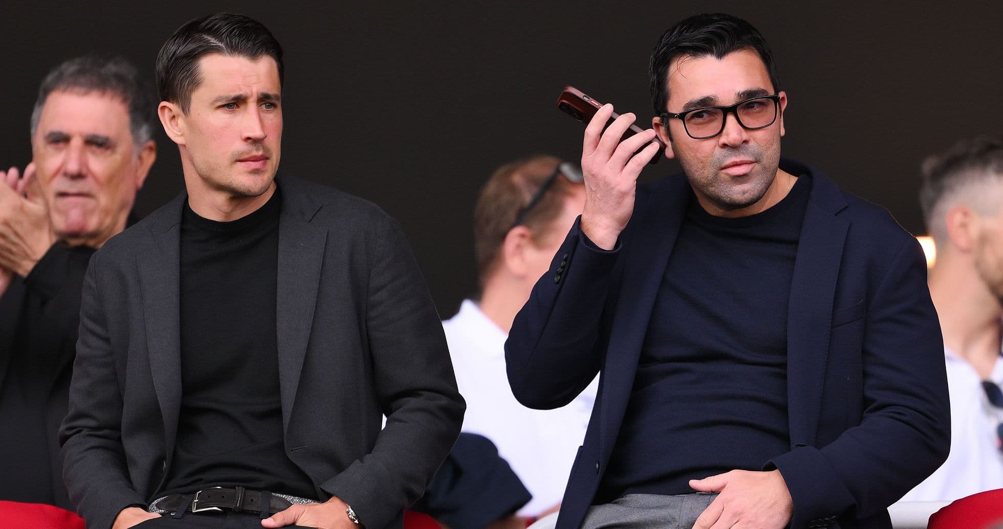 Two men seated in a sports venue watching event Two men seated in a sports venue watching event