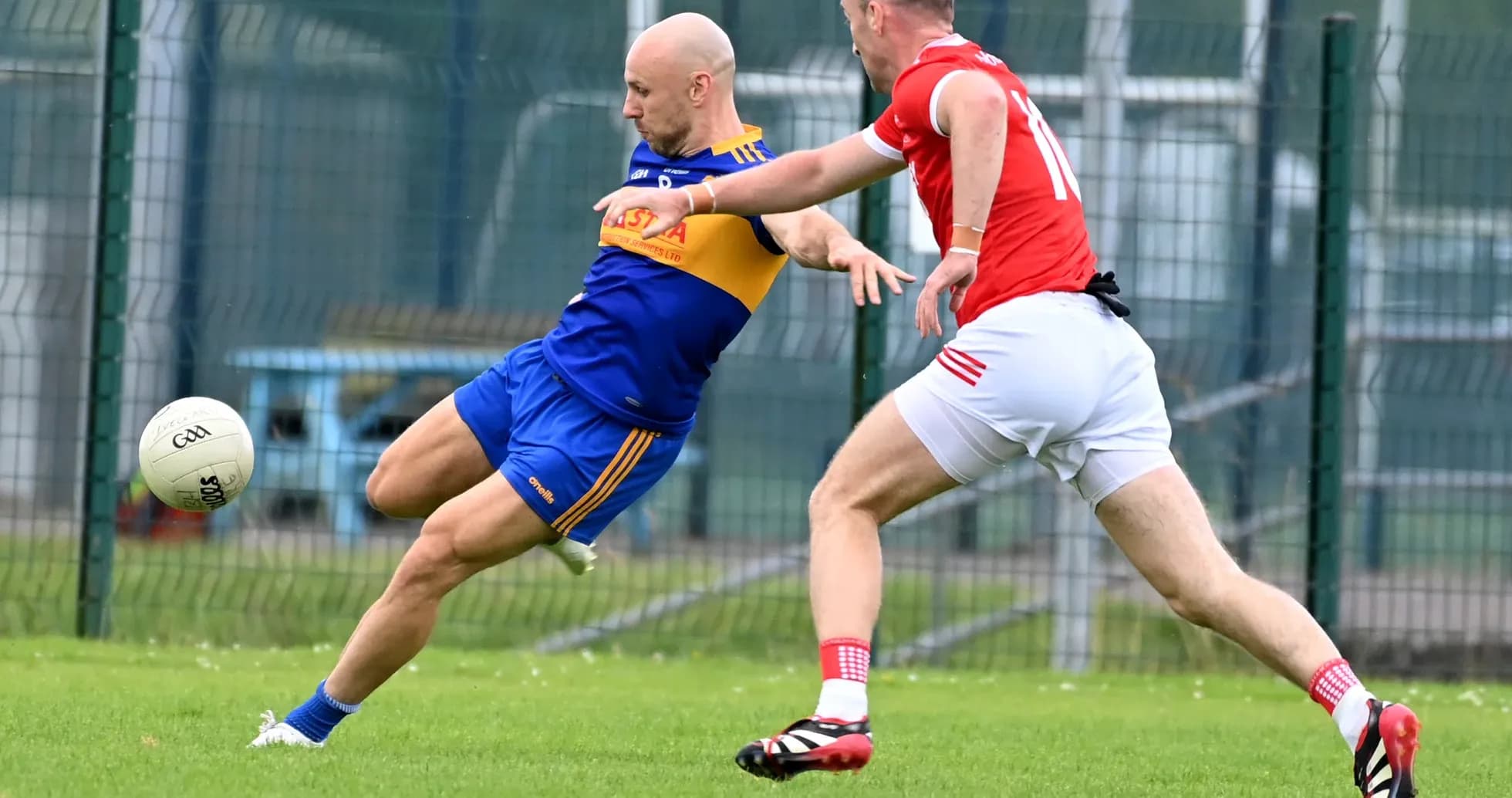 Player kicking a ball while being challenged by opponent Player kicking a ball while being challenged by opponent
