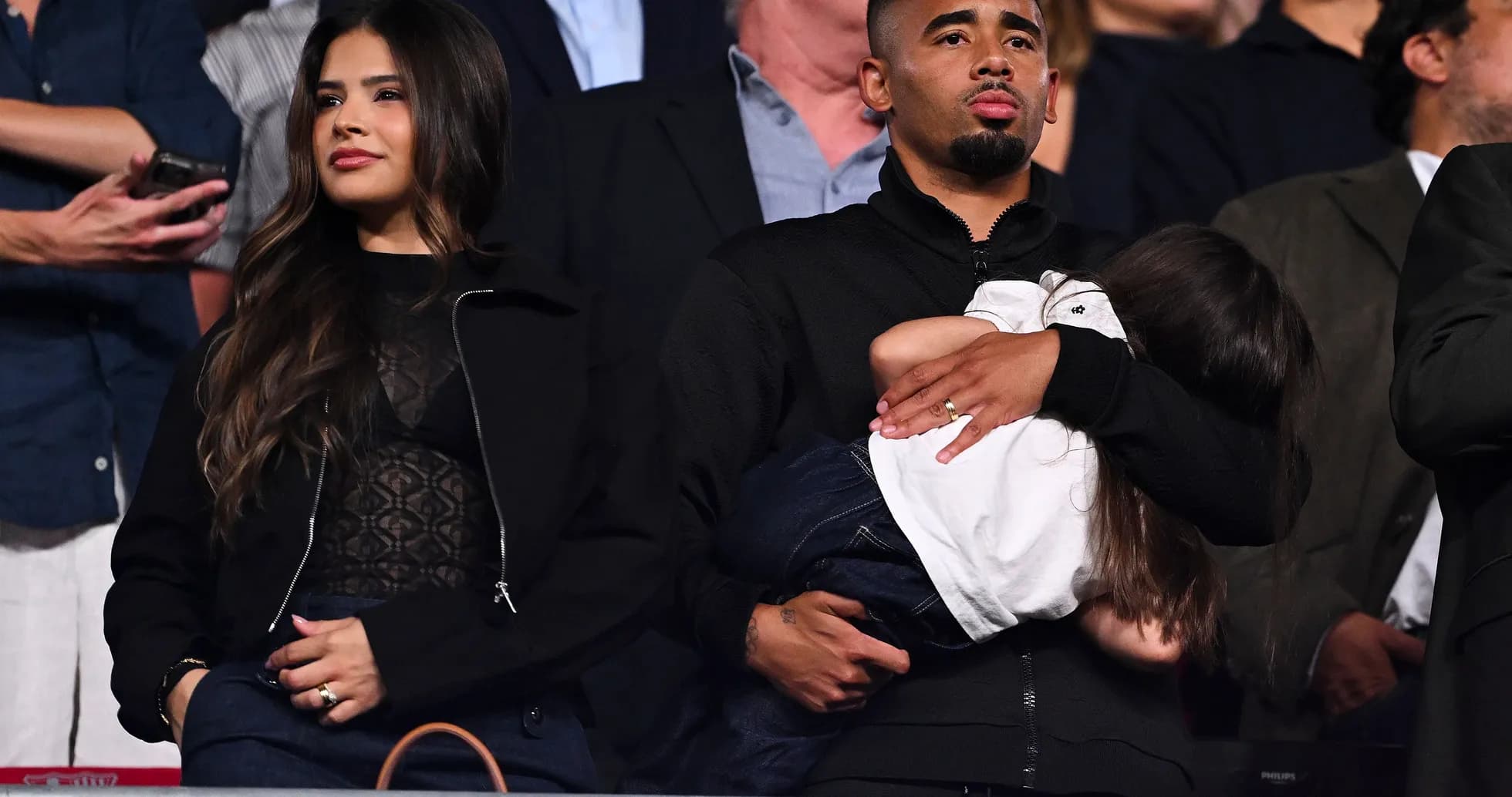 Man holding child, woman standing beside him Man holding child, woman standing beside him