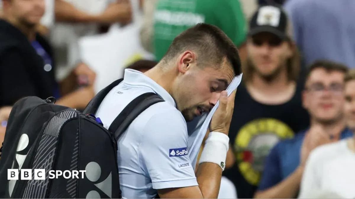 Player wiping sweat during tennis match Player wiping sweat during tennis match