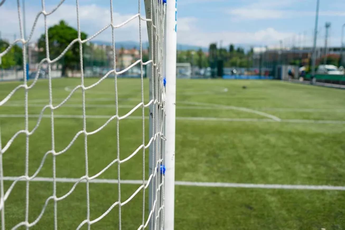 Close-up of soccer goal with field in background Close-up of soccer goal with field in background