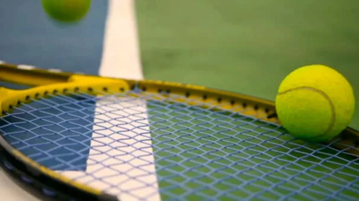 Tennis ball resting on racket near court lines Tennis ball resting on racket near court lines