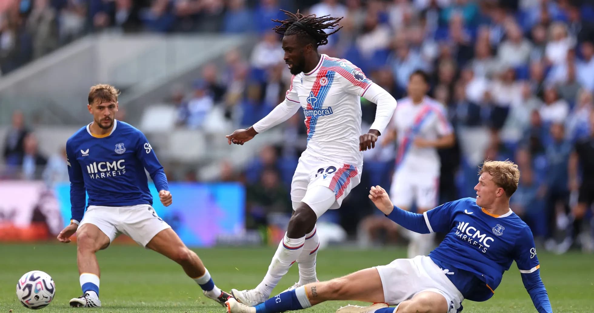 Player in white dribbling past two defenders in blue Player in white dribbling past two defenders in blue