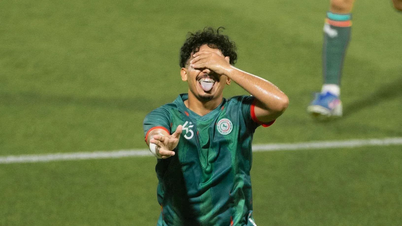 Player celebrating goal with playful gesture on field Player celebrating goal with playful gesture on field