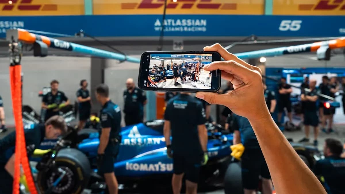 Team working on car in garage, phone capturing scene Team working on car in garage, phone capturing scene