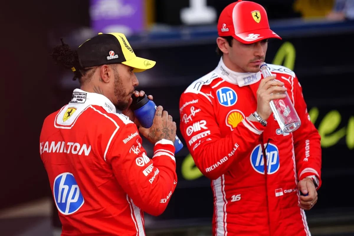 Two drivers in red suits drinking water bottles Two drivers in red suits drinking water bottles