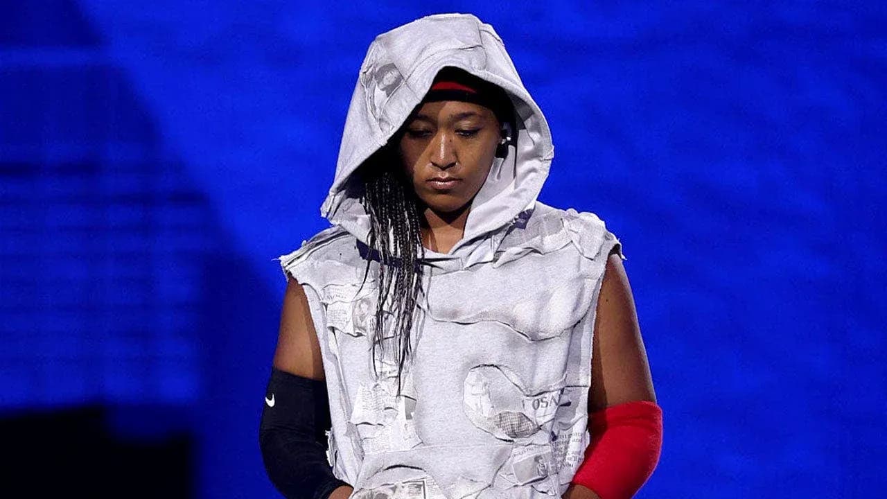 Athlete wearing a hooded, torn outfit on stage Athlete wearing a hooded, torn outfit on stage