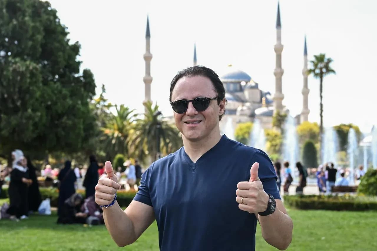 Person giving thumbs up in park with mosque Person giving thumbs up in park with mosque