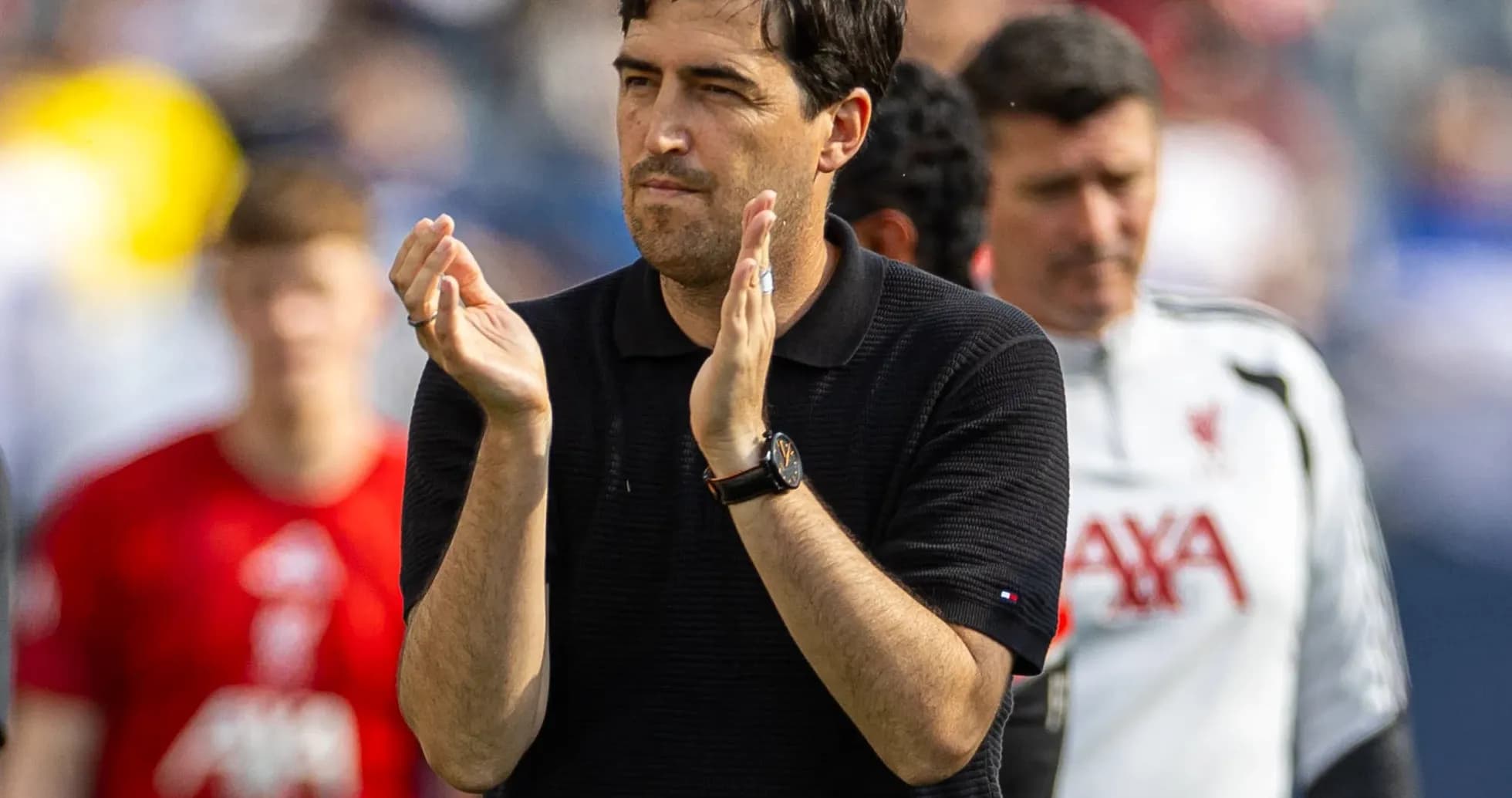 Coach applauding during match with players in background Coach applauding during match with players in background