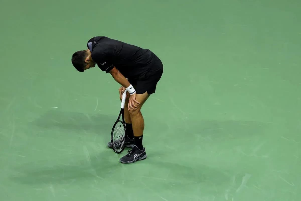 Player bent over holding tennis racket on court Player bent over holding tennis racket on court