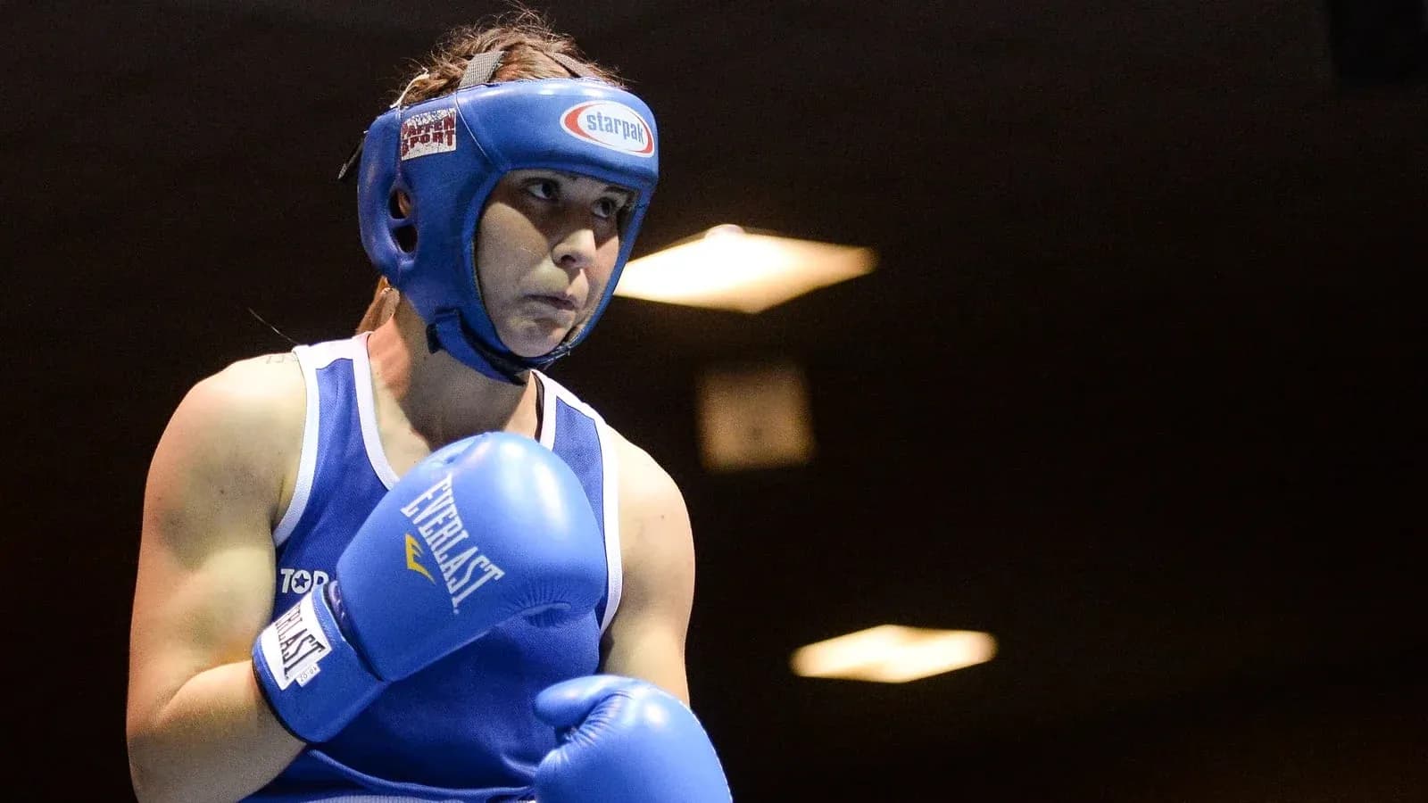 Female boxer in blue gloves preparing to fight Female boxer in blue gloves preparing to fight