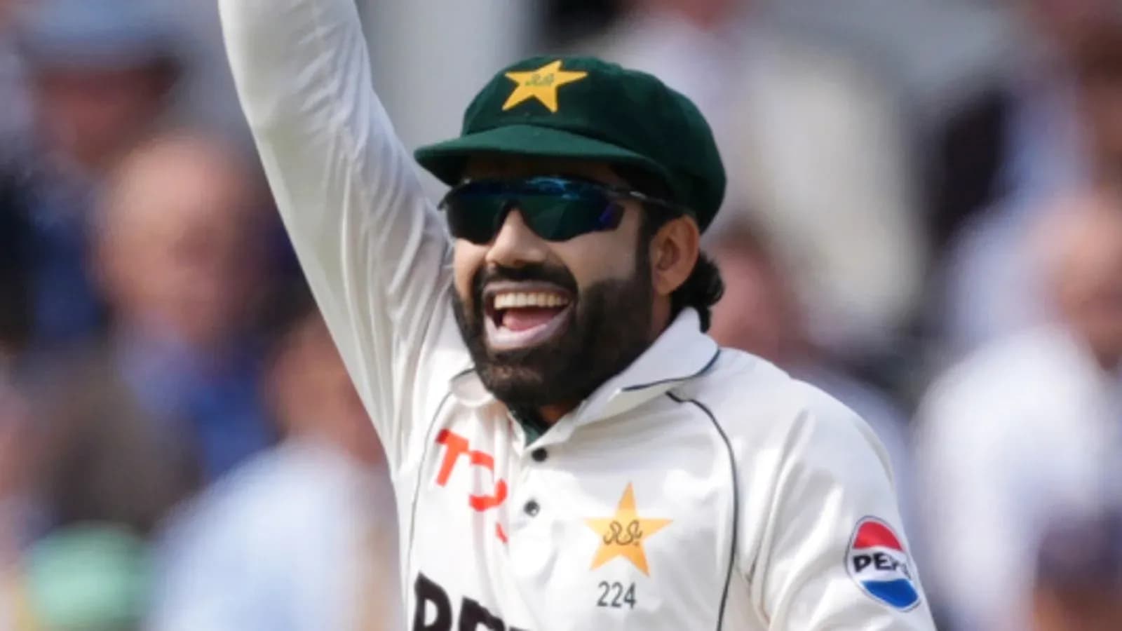 Cricketer celebrating with raised hand on field Cricketer celebrating with raised hand on field
