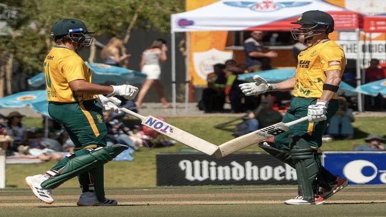 Two cricket players celebrating with their bats Two cricket players celebrating with their bats