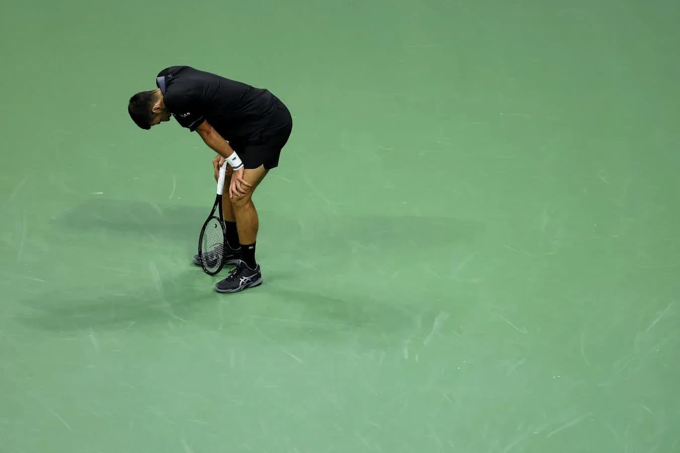 Tennis player bending over on court with racket Tennis player bending over on court with racket